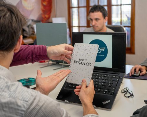 Empleados mirando agenda de Peñaflor, en oficina HyF Distribuidora, distribuciones