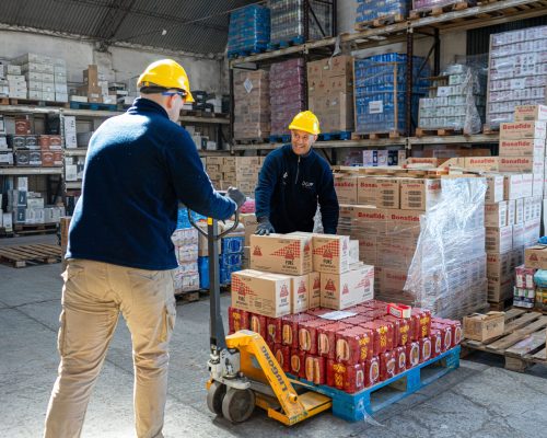 Empleados trasladando mercadería, con unas cajas de pure, Bonafide, cervezas sol de oro Antares